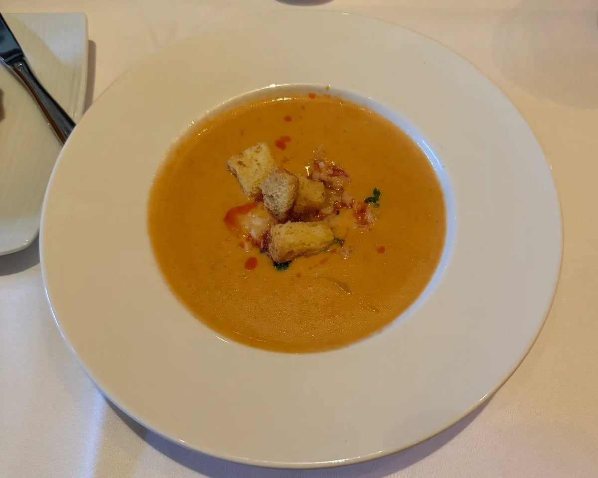 Cremet hummerbisque med hummerkød og croutoner i en hvid tallerken