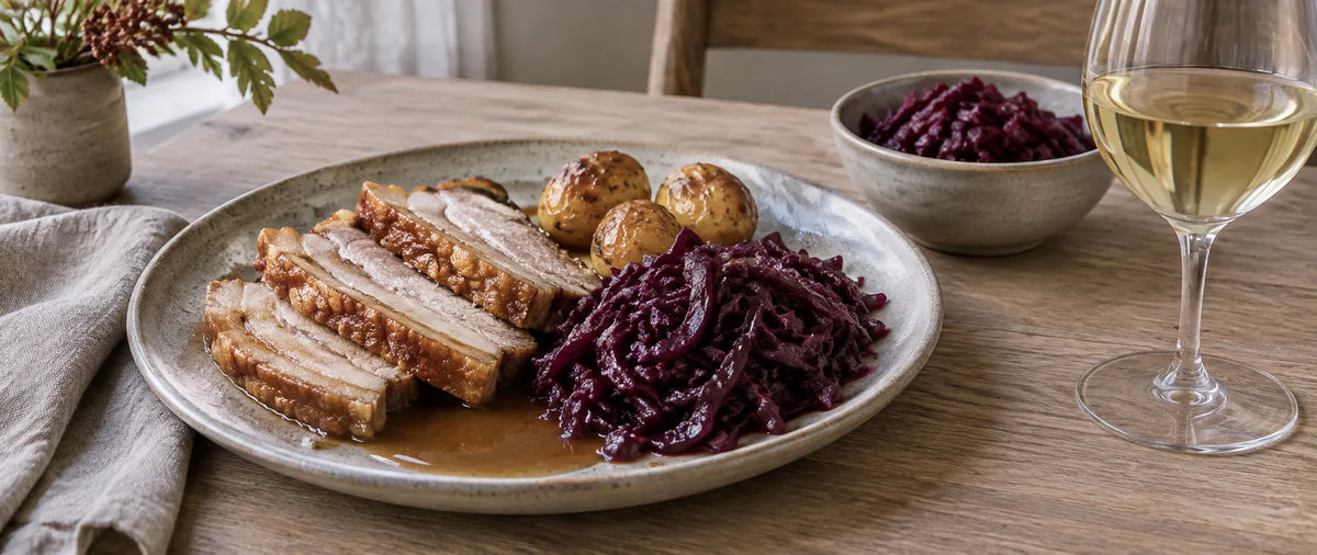 Flæskesteg med sprød svær, rødkål, brunede kartofler, sovs og et glas hvidvin