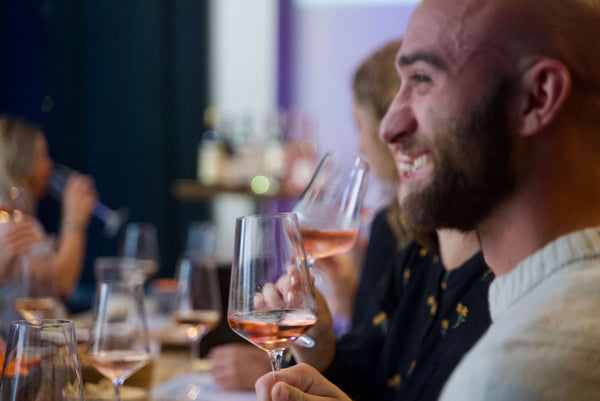 Glad gæst nyder et glas spansk rosévin og den gode stemning til en vinsmagning hos DeVinos i Aarhus.