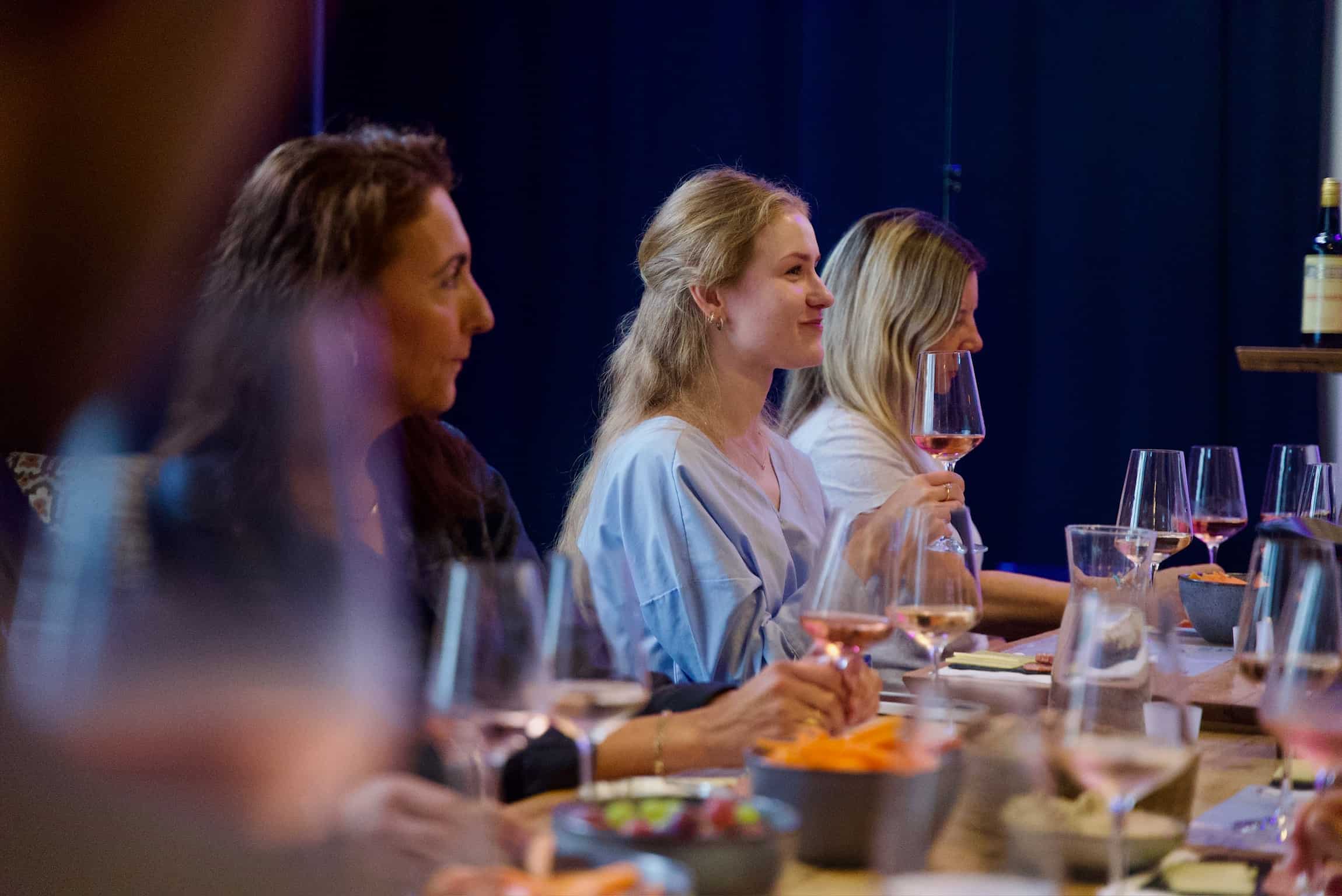En gruppe veninder fordybet i en social og lærerig spansk vinsmagning, arrangeret af DeVinos i Aarhus.